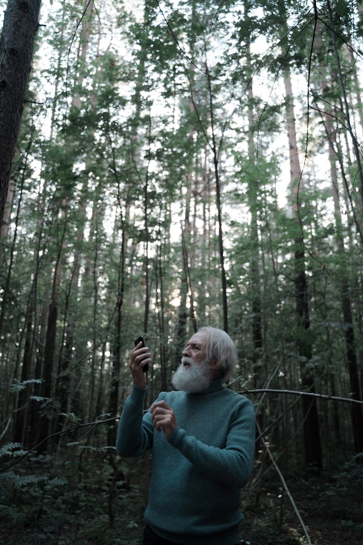 Man In Green Sweater Lost In Forest Using Smartphone