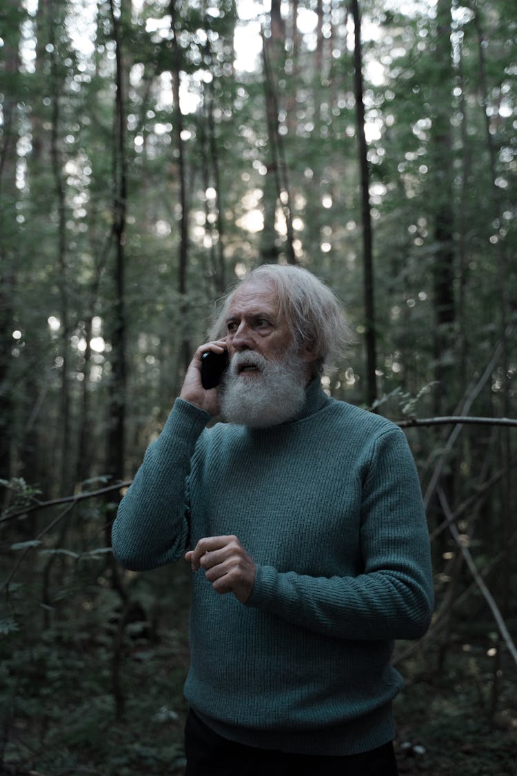 Scared Man In Green Sweater Lost In The Forest Using Mobile Phone