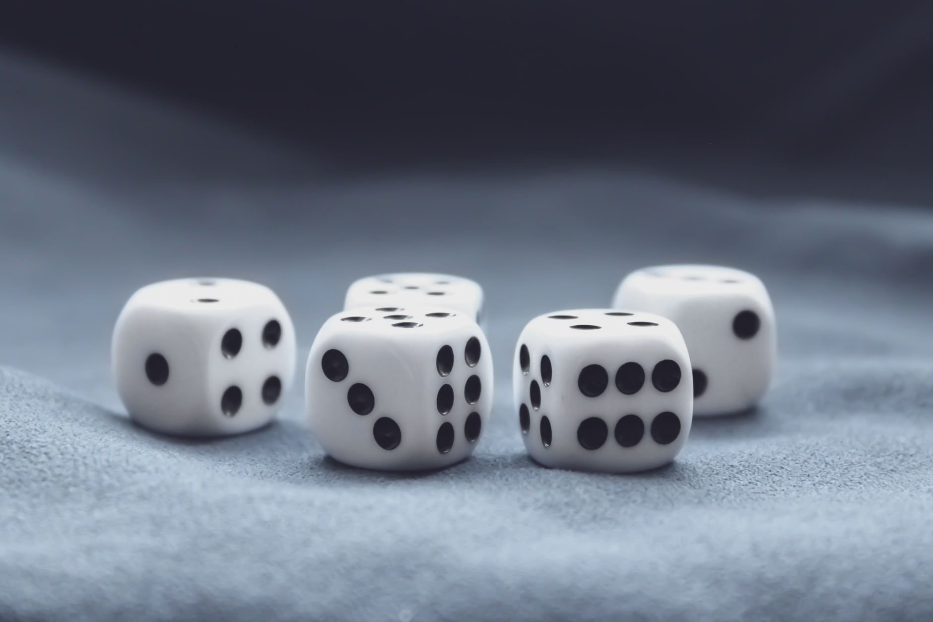 A collection of five white dice on a soft, textured background. Perfect for gaming themes.