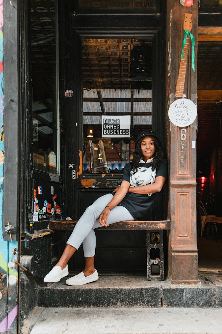 Woman Sitting By The Entrance Of A Bar