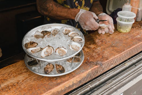 Free Mans Gloved Hands Preparing Fresh Oysters in Restaurant Stock Photo
