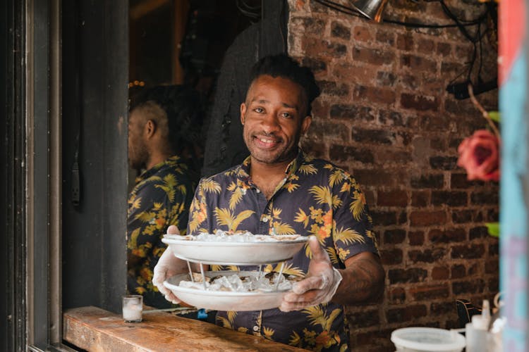 Man In Gloves Holding Plates Of Seafood