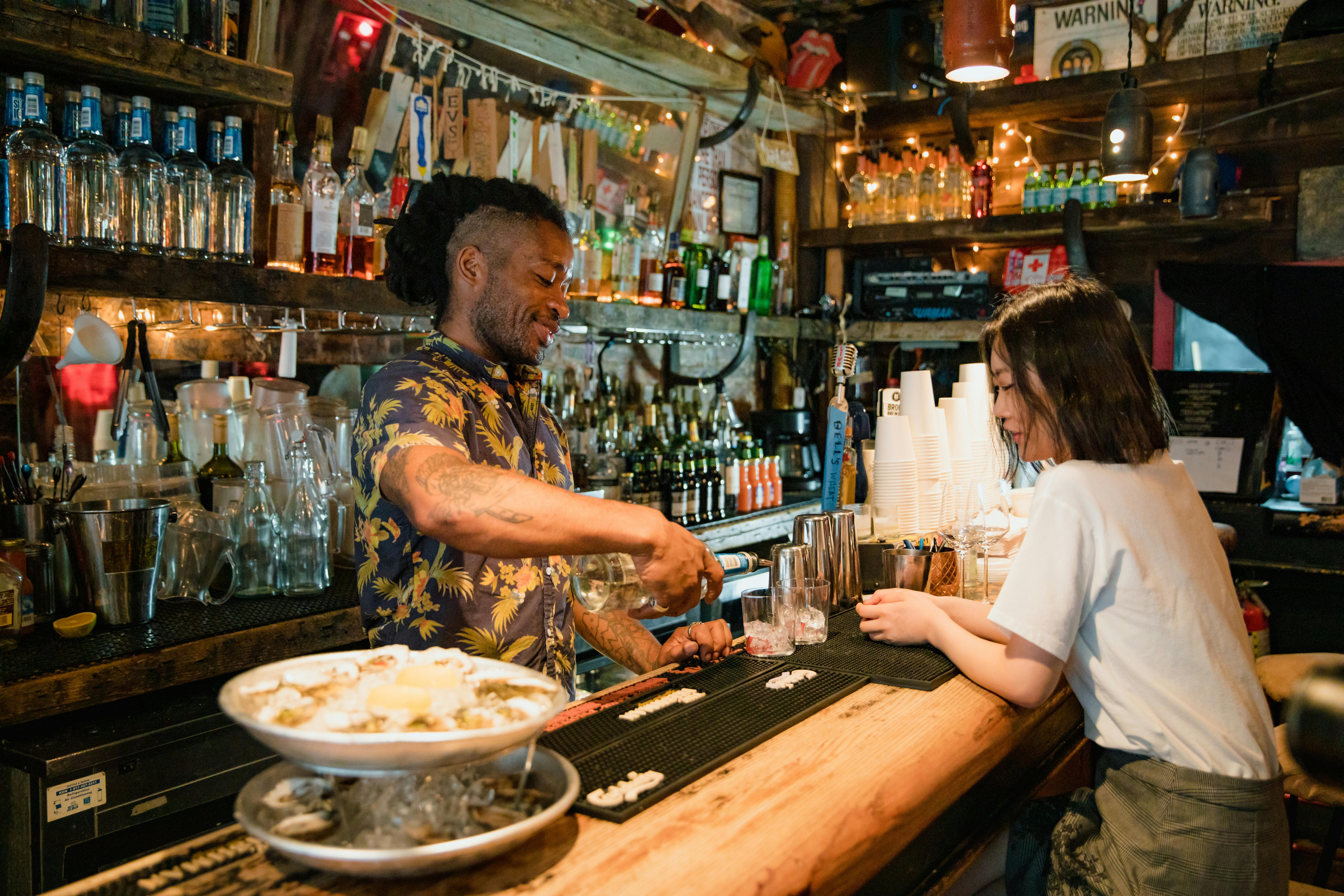 bartender preparing cocktail for customer at bar