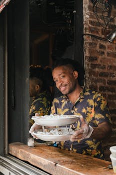 Chef in Hawaiian shirt proudly presenting seafood on crushed ice at restaurant counter.