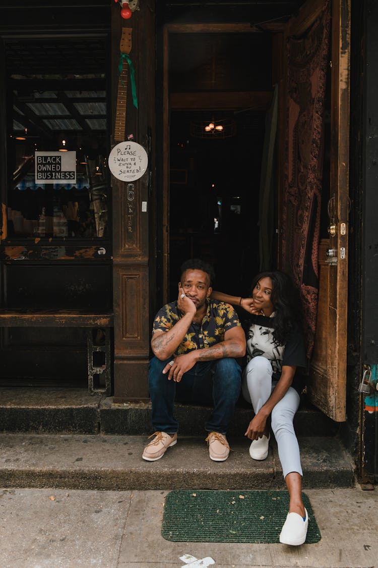 Man And Woman Sitting At Entrance To Bar