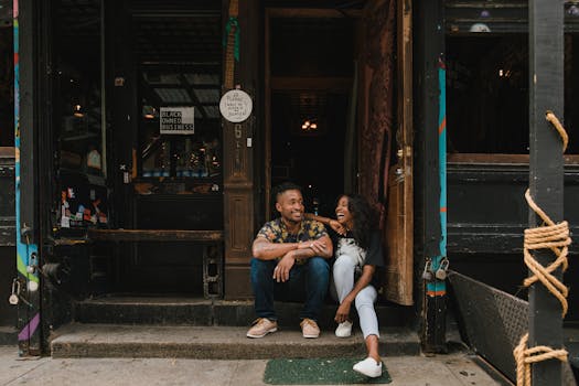 Friendly moment outside a black-owned café with two owners sitting at the entrance, showcasing community pride.