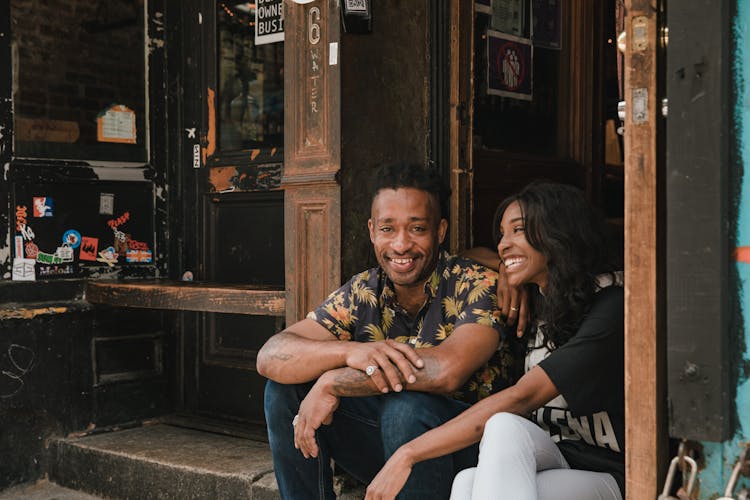 Man And Woman Sitting At Entrance To Bar