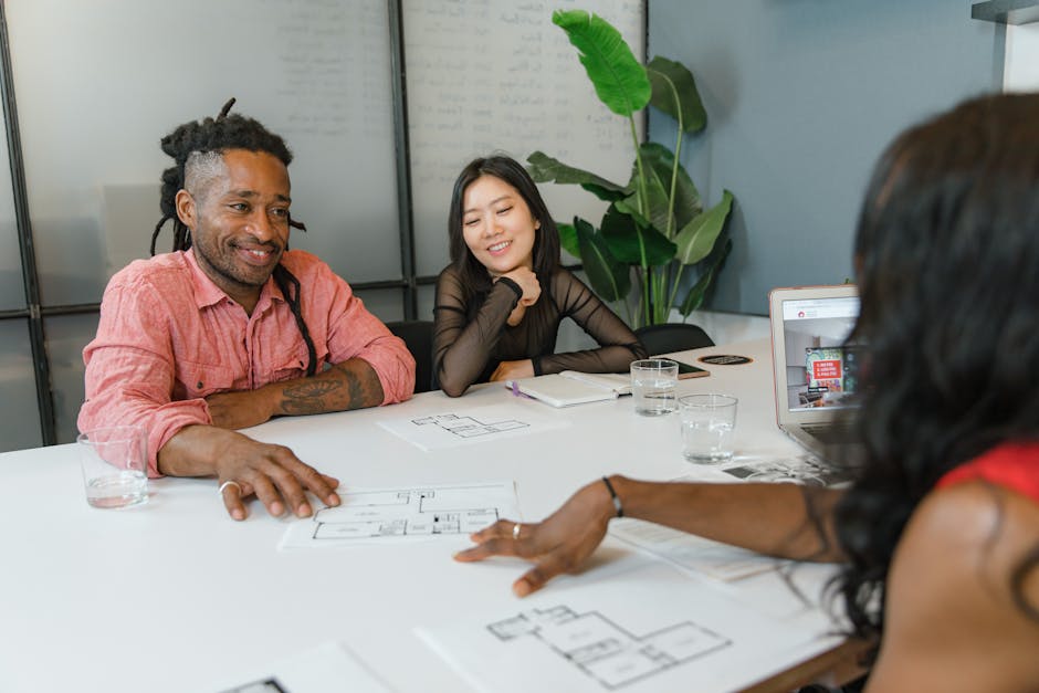 A diverse group of colleagues engaging in a planning session with architectural blueprints in a modern office setting.