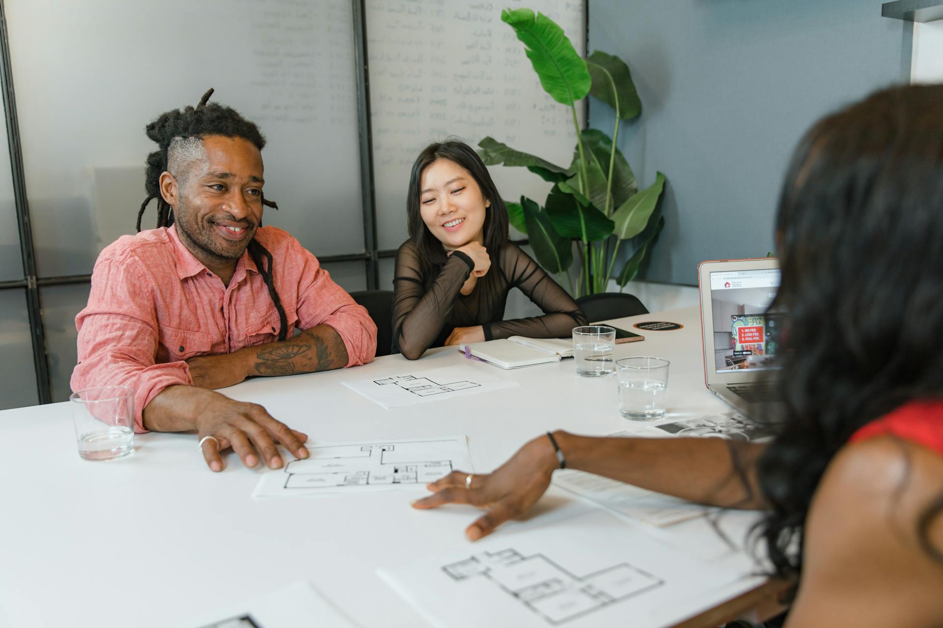 A diverse group of colleagues engaging in a planning session with architectural blueprints in a modern office setting.