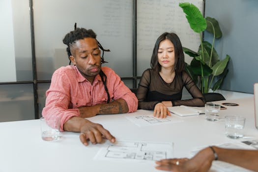 A diverse team discusses a blueprint during an office meeting, focusing on collaborative planning.