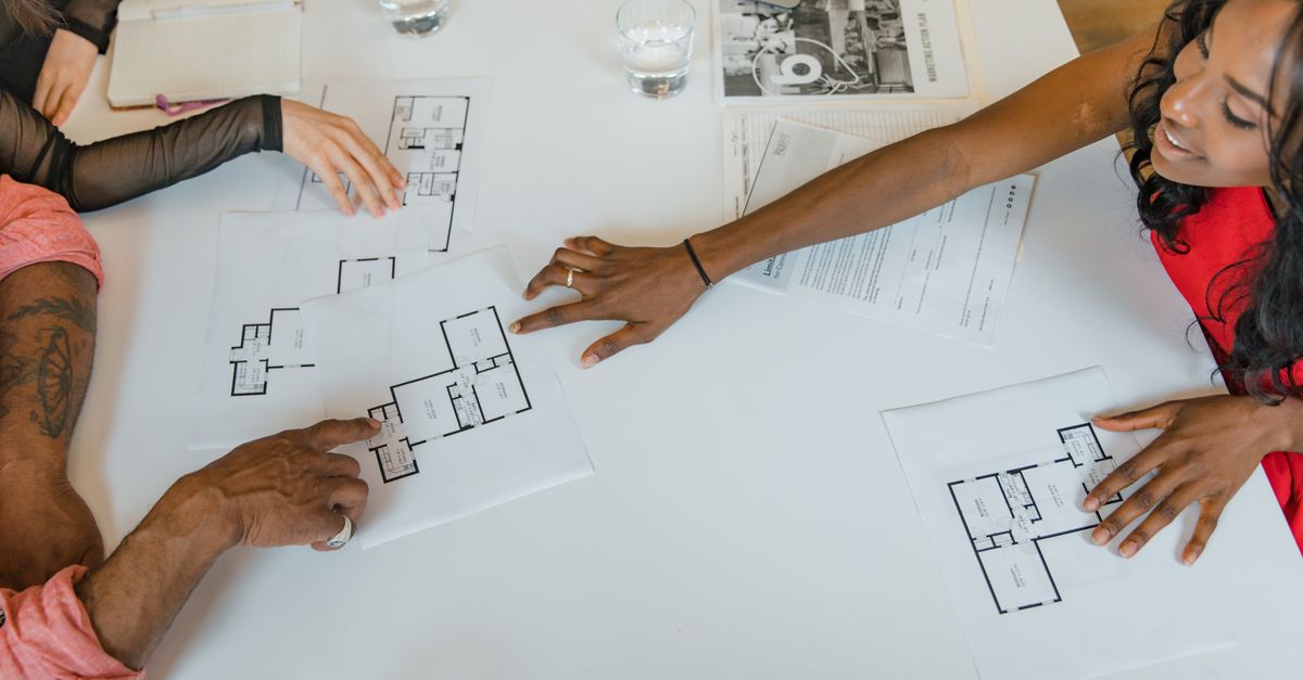 High angle view of diverse business team discussing architectural plans around a table.