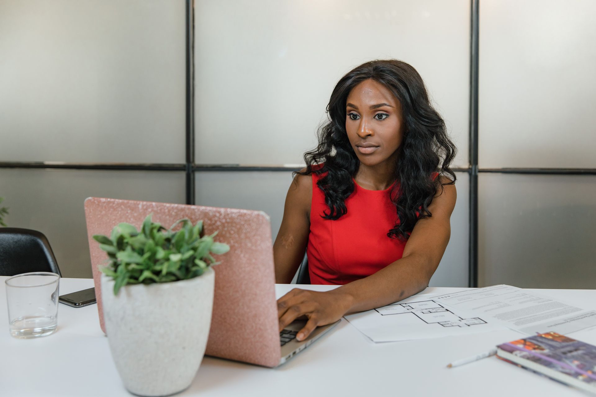 Focused businesswoman using laptop in office setting, emphasizing professional work environment.