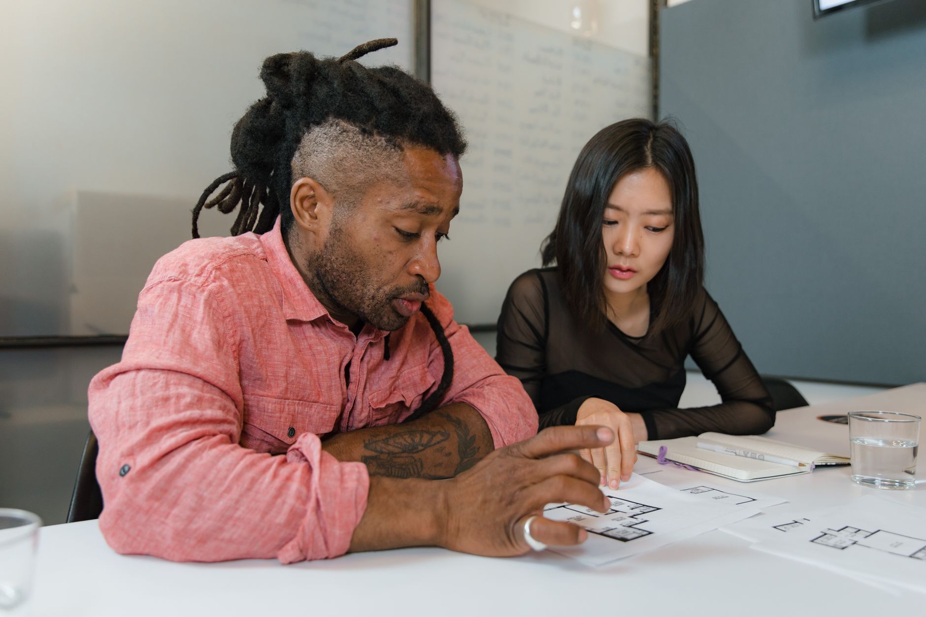 Two professionals engaged in planning during a business meeting, focusing on architectural designs.