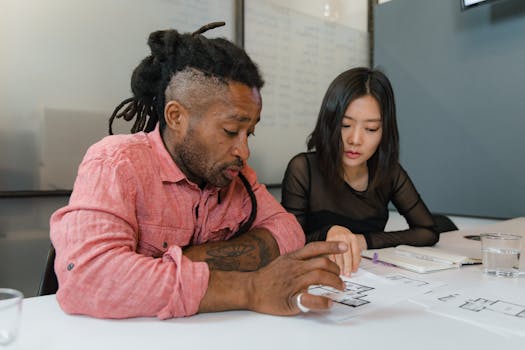 Two professionals engaged in planning during a business meeting, focusing on architectural designs.