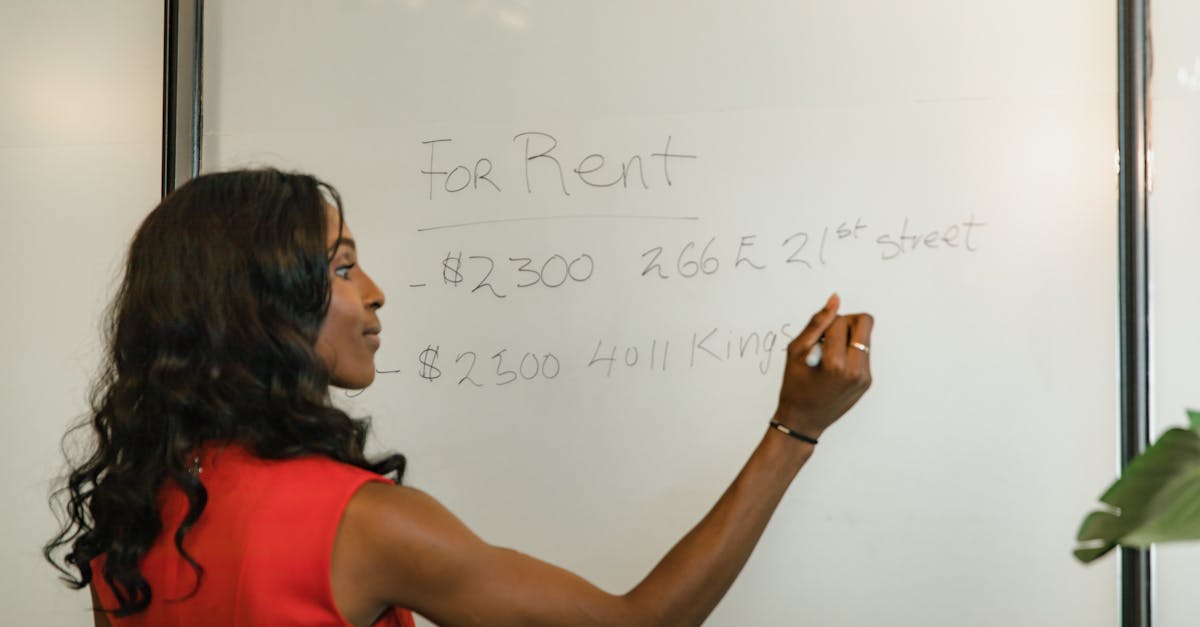 Photo by RDNE Stock project Professional woman writing real estate prices on a whiteboard for rental properties.