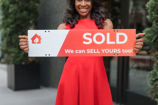 Smiling woman holding a 'Sold' sign, symbolizing successful real estate sales.
