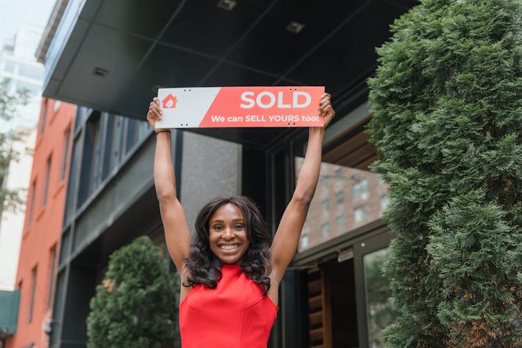 Smiling Woman In Red Dress Holding Sign