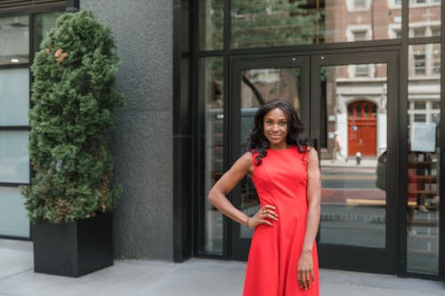 Smiling woman in red dress in front of office building