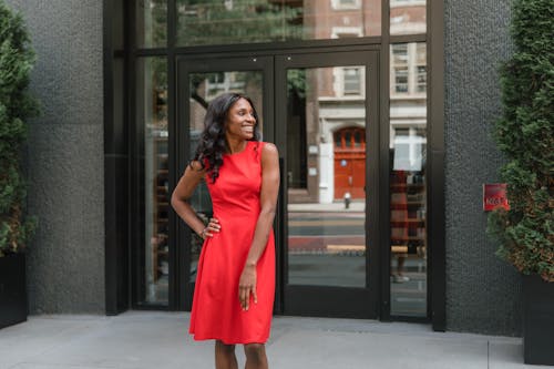 Smiling woman in red dress standing in front of office building