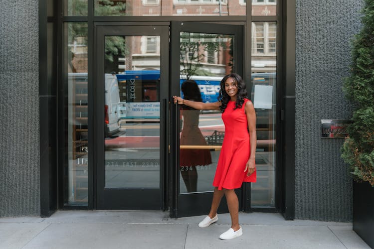 Smiling Woman Opening Door To Office Building