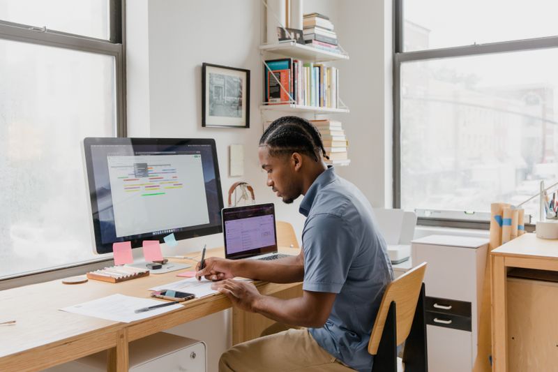 Professional working at a desk with multiple computer screens in a modern office