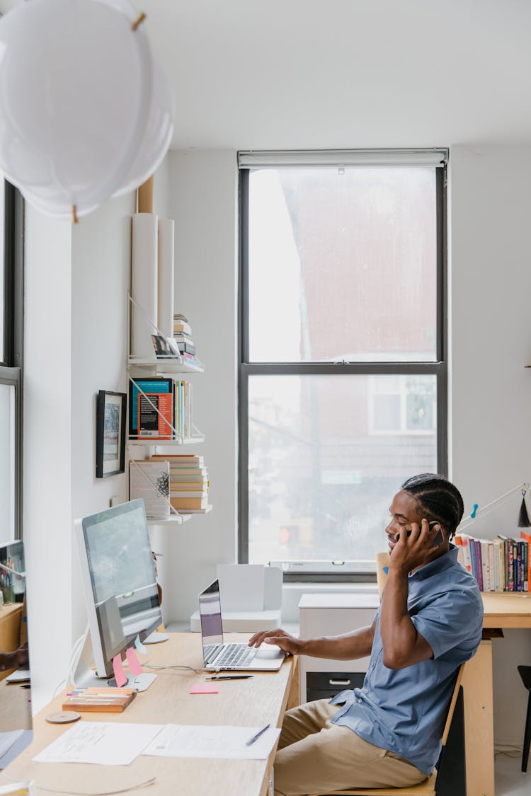 Man Sitting At Desk In Office, Talking On Phone