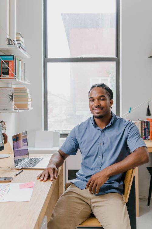 Free A cheerful man sitting at a desk with a laptop in a bright home office. Stock Photo