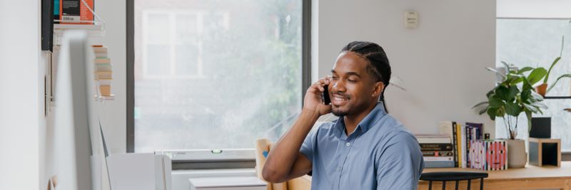Adult man engaged in office work, speaking on phone, showcasing a professional environment.