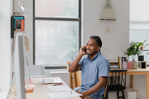 Free Adult man engaged in office work, speaking on phone, showcasing a professional environment. Stock Photo