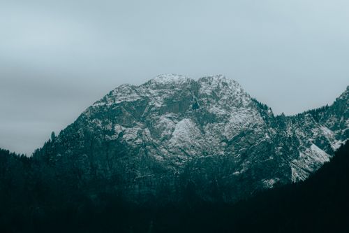 Free Breathtaking view of a snow-capped mountain peak under a cloudy winter sky. Stock Photo