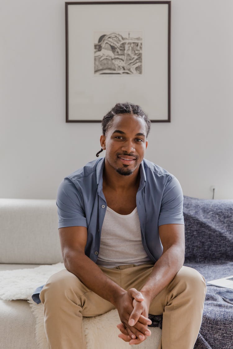 Smiling Man In Braids Sitting On Couch