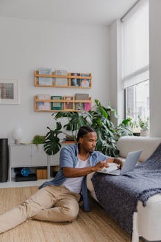 Adult man working on laptop in a modern, cozy home interior with plants.