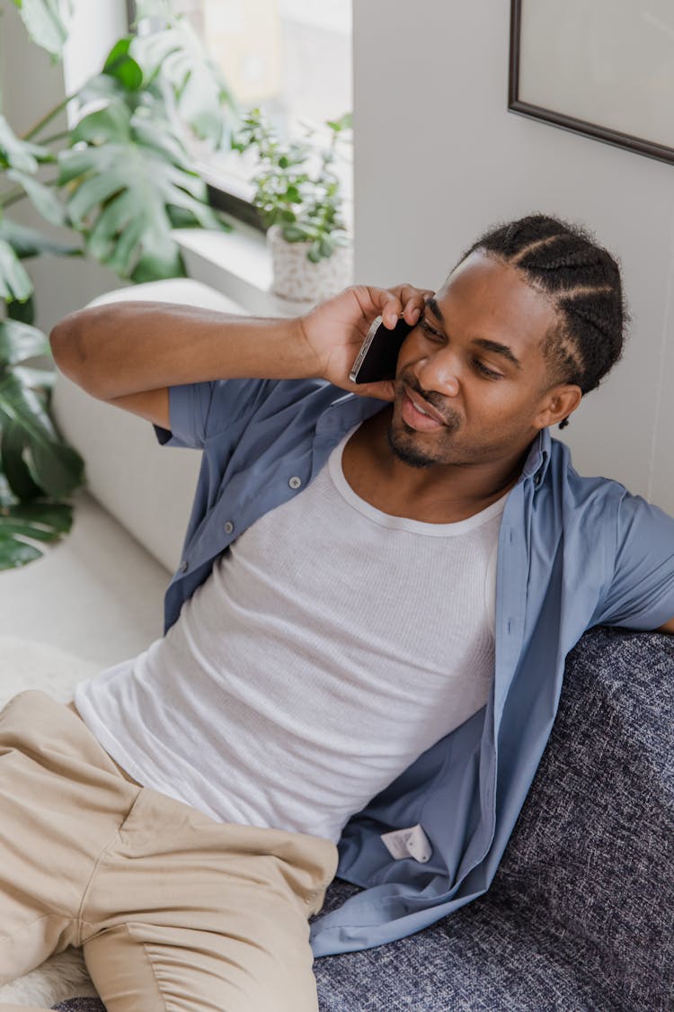 Man In Shirt Sitting On Sofa And Talking On Phone