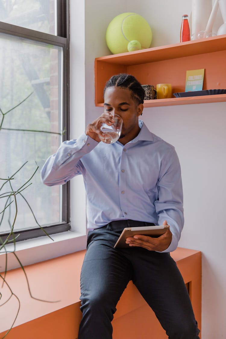 Portrait Of Man Drinking Water And Holding Tablet