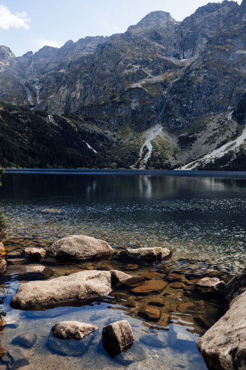 Free Calm lake surrounded by majestic Tatra mountains reflecting natural beauty in Poland. Stock Photo