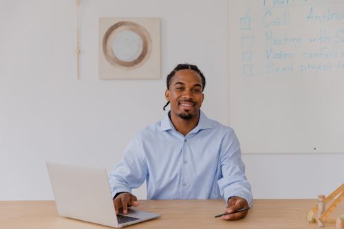 Free Confident businessman smiling while working on a laptop at his office desk. Stock Photo