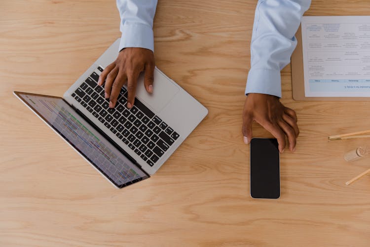 Hands Of Man Working On Laptop And Smart Phone