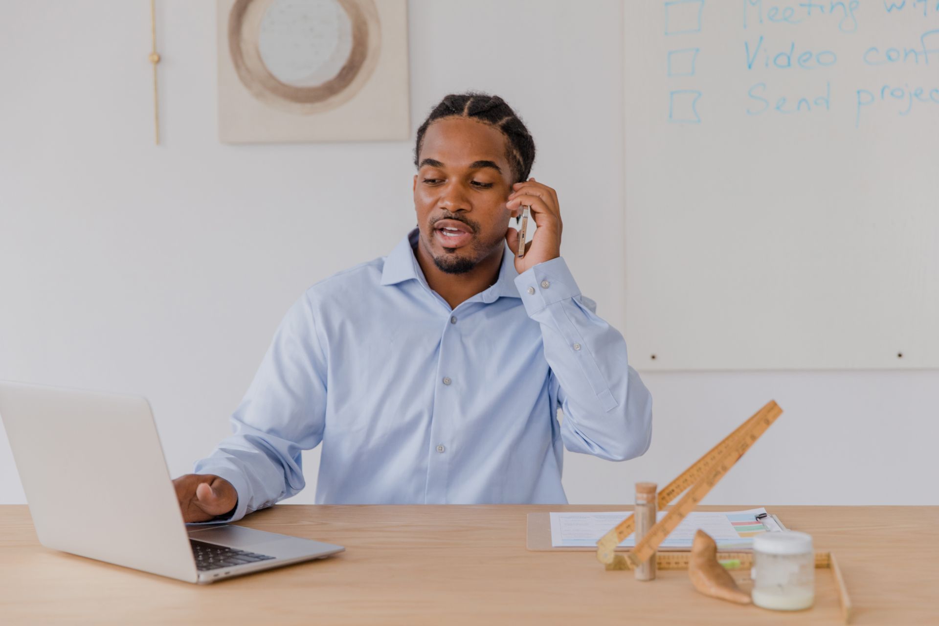 Businessman on a phone call working at a desk with laptop and office supplies.