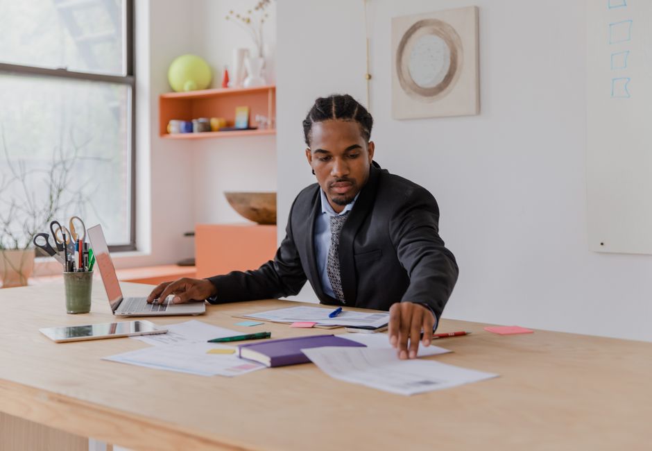 Focused businessman in office organizing documents at a modern desk.