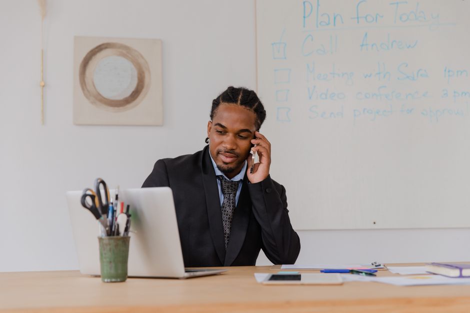 A businessman making a phone call in a modern office setting, working at a desk.