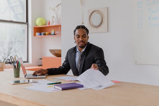 Professional businessman in a suited attire working at his desk with documents and laptop.