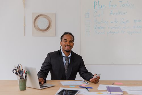 Free Professional man with braided hair working on a laptop in a modern office. Stock Photo