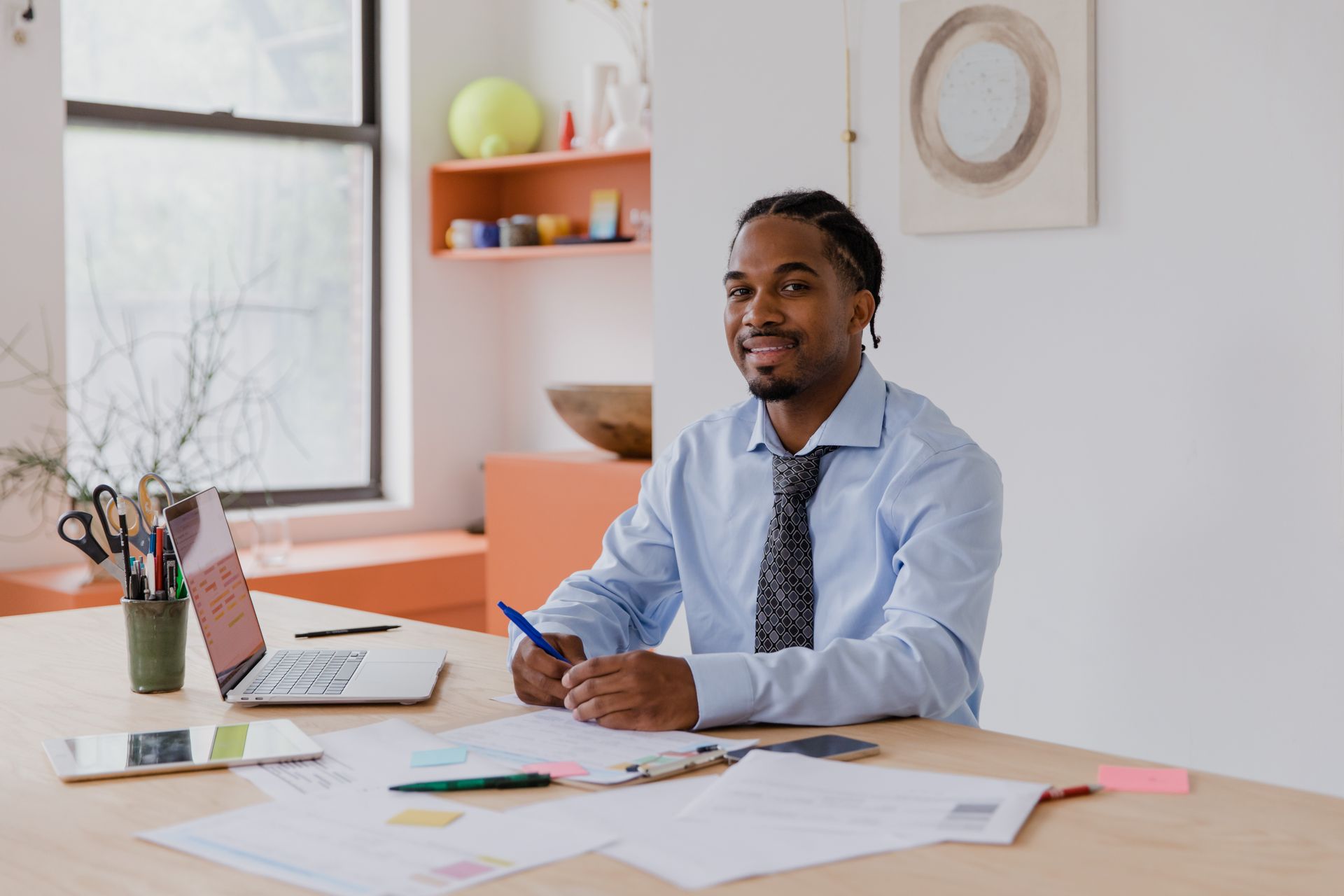 Confident black male entrepreneur smiling while working at desk in modern office.
