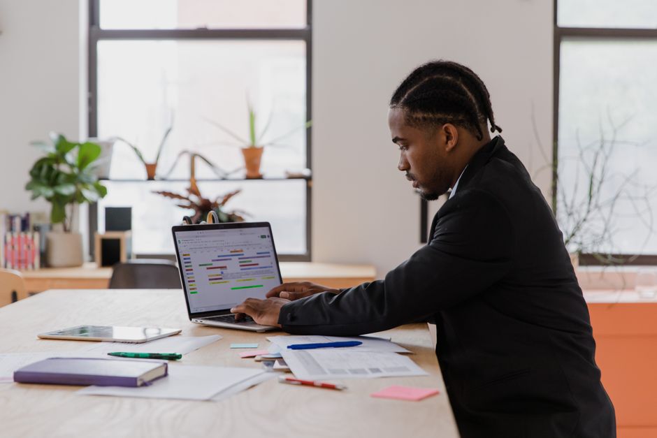 Businessman with braided hair focused on laptop work at office desk. Businessman with braided hair focused on laptop work at office desk.