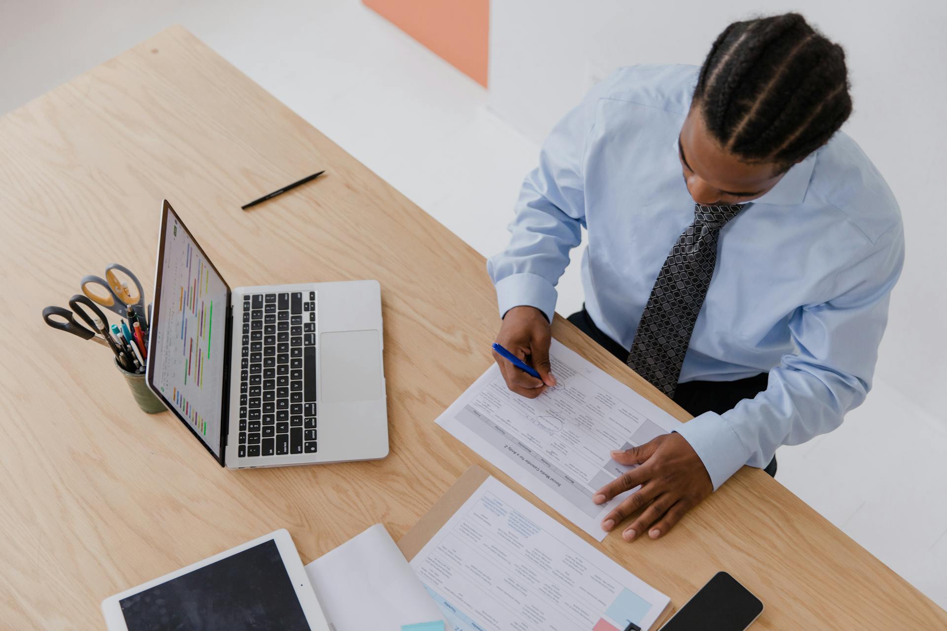 Man Writing on Documents while Sitting at his Desk