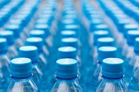 Array of blue plastic water bottles with caps arranged in a pattern. Ideal for recycling and packaging themes.