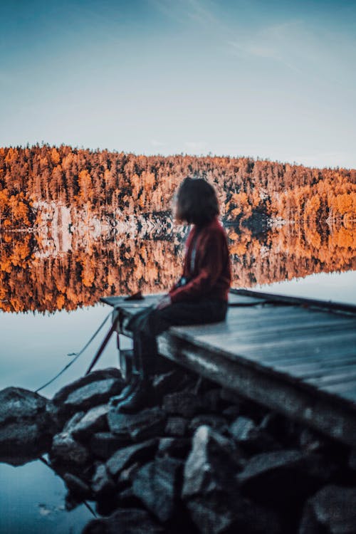 Free Person Sitting on Wooden Dock Looking at the Lake Stock Photo