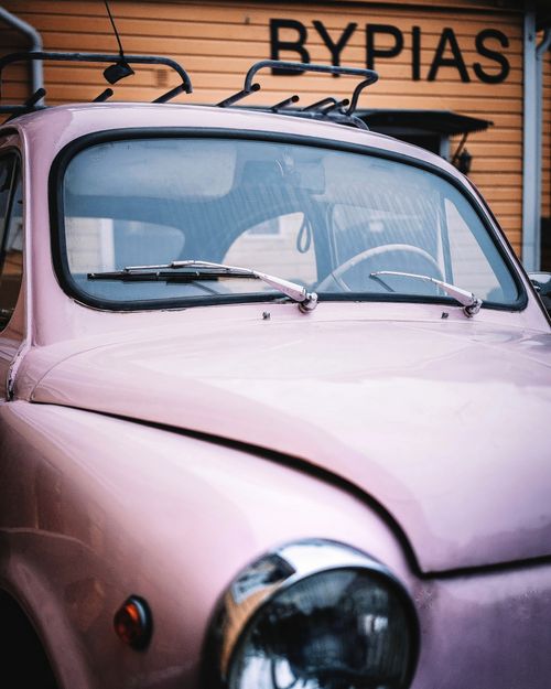 Free Close-up of a vintage pink car parked outside a wooden house with Bypias sign. Stock Photo