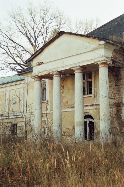 Free An abandoned mansion with a weathered facade and classic architecture stands amidst overgrown grass. Stock Photo