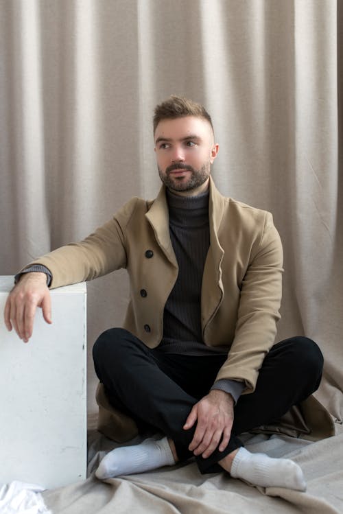 Man in Brown Coat Sitting on Floor 